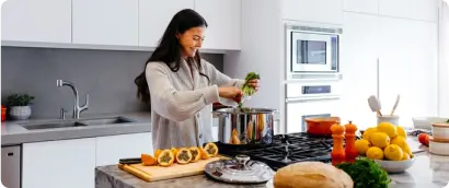 Woman in kitchen making fresh fruit salad
