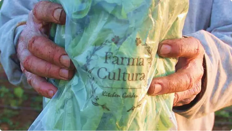 farmer holding a bag of FARMA Cultura branded biodegradable packaging