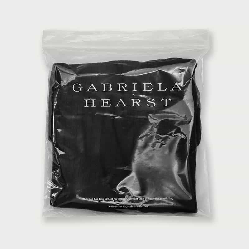 sustainable gabriela hearst branded zipper bag with black clothes inside
