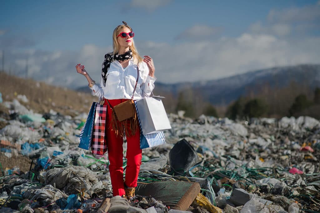 Woman with shopping bags standing on a landfill